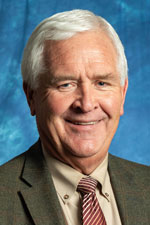Image of Dr. Steven Fraze, Department Head and Professor in the Department of Agricultural and Extension Education at NMSU. Dr. Fraze has grey hair and is wearing a grey suit jacket over a white button up shirt with a red and white striped tie
