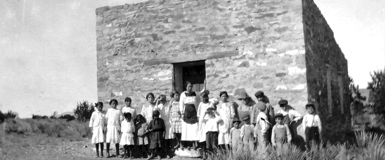 Fabiola standing in front of the stone building with her students